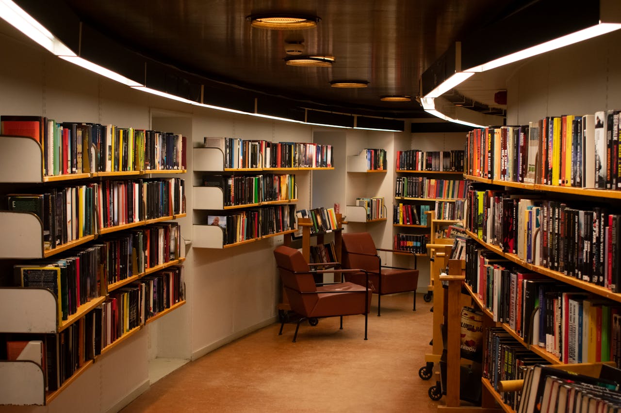 A cozy library space in Stockholm with brown leather chairs and wooden bookshelves filled with books.